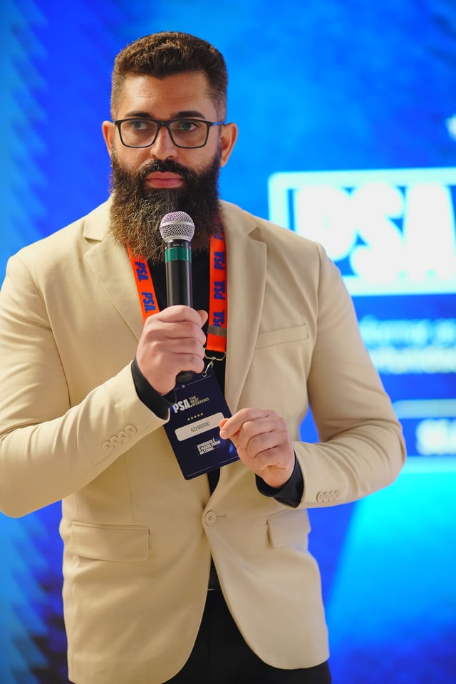Alex Missiano com microfone durante palestra em evento corporativo.